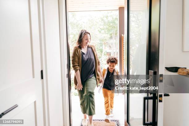 moeder en zoon die door deur samen lopen. terug naar school moment - betreden stockfoto's en -beelden
