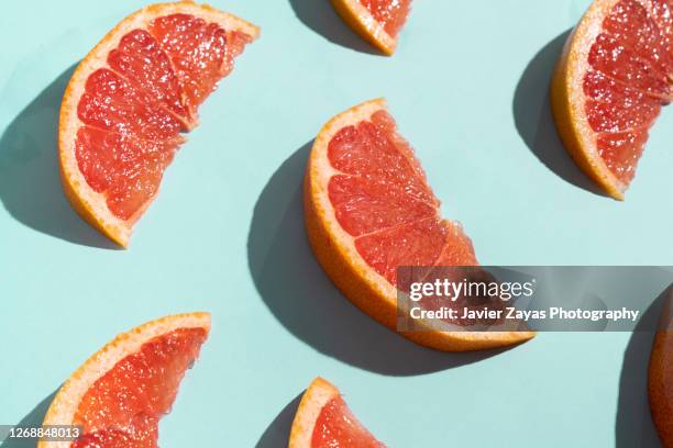 grapefruit slices on turquoise background - bright food stock pictures, royalty-free photos & images