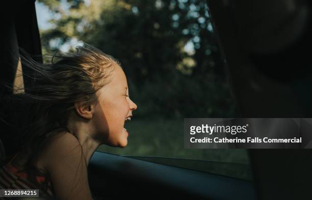beautiful happy little girl enjoying a car journey as the wind blows through her hair - aufregung stock-fotos und bilder