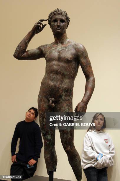Visitors look at a statue of the Victorious Youth, who was recovered from a first-century BC shipwreck in the Adriatic Sea off the coast of Italy, at...