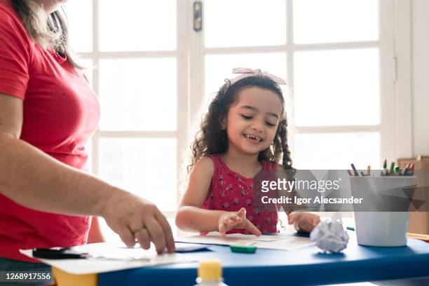 menina sorridente fazendo lição de casa junto com sua mãe - human representation - fotografias e filmes do acervo