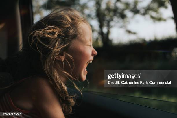 beautiful happy little girl enjoying a car journey as the wind blows through her hair - girl traveler stock pictures, royalty-free photos & images