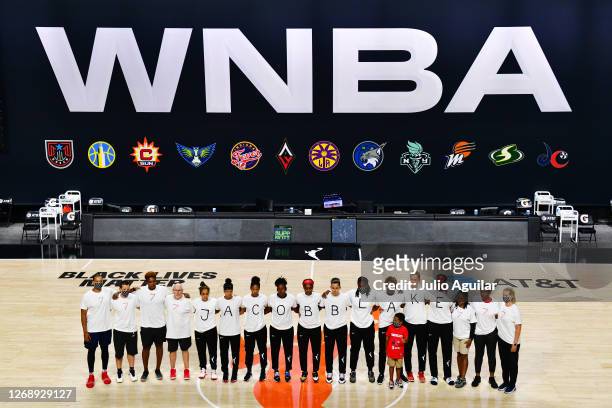 After the WNBA announcement of the postponed games for the evening, the Washington Mystics each wear white T-shirts with seven bullets on the back...