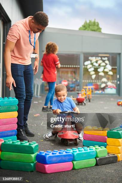 nursery worker with child in playground - preschool stock pictures, royalty-free photos & images