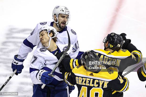 Matt Grzelcyk and Jeremy Lauzon of the Boston Bruins scuffle with Yanni Gourde of the Tampa Bay Lightning during the second period in Game Three of...