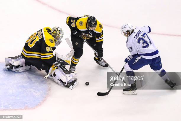 Dan Vladar and Jeremy Lauzon of the Boston Bruins defend against Yanni Gourde of the Tampa Bay Lightning during the second period in Game Three of...