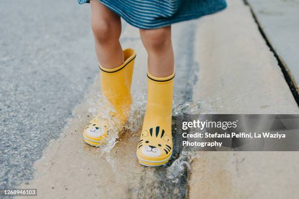 close up of feet wearing boots while jumping in puddles - rain boots stock pictures, royalty-free photos & images