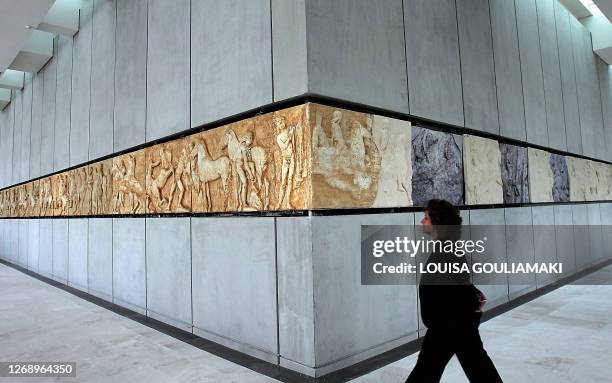 Woman walks by zoforos relief from the Parthenon Temple displayed in the Pathenon Hall inside the new Acropolis Museum in Athens 10 January 2008. The...