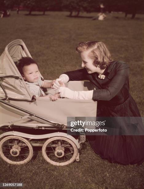 Ruth Williams Khama , wife of Seretse Khama, Chief of the Bamangwato people of Bechuanaland , holds the hand of their daughter Jacqueline in her pram...