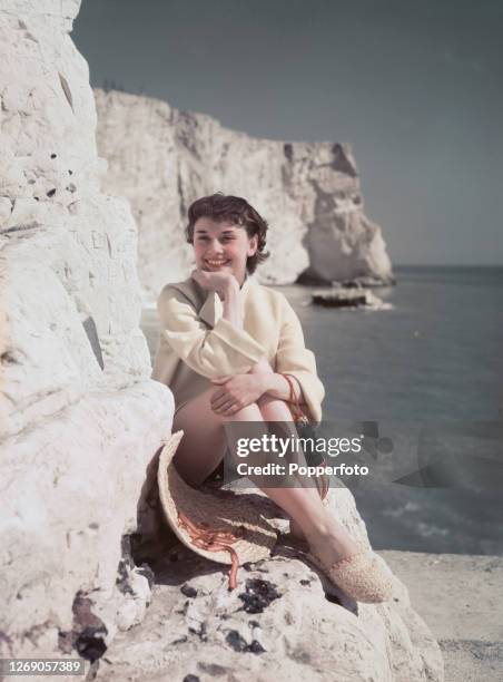 Belgian born British actress and dancer Audrey Hepburn posed with straw hat and espadrilles sitting on the chalk cliffs by the English Channel near...