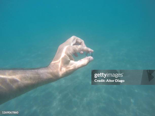 man diving under the sea water holding a wedding ring almería, spain. - 25th wedding anniversary stock pictures, royalty-free photos & images