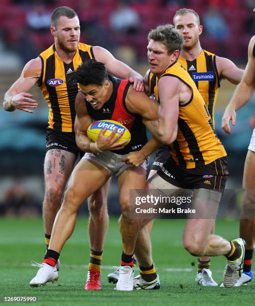 Dylan Shiel of the Bombers tackled by Ben McEvoy of the Hawks and Blake Hardwick of the Hawks during the round 14 AFL match between the Hawthorn...