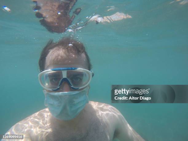 underwater portrait of a man diving with goggles and a protective mask on. spain. almeria. - funny surgical masks stockfoto's en -beelden