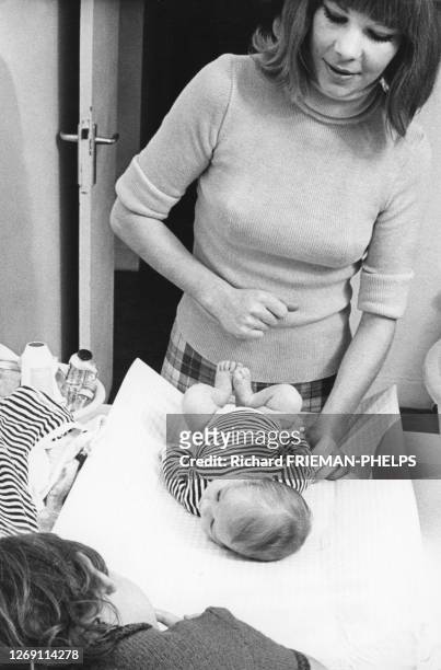Femme changeant la couche de son bébé, en 1972, France.