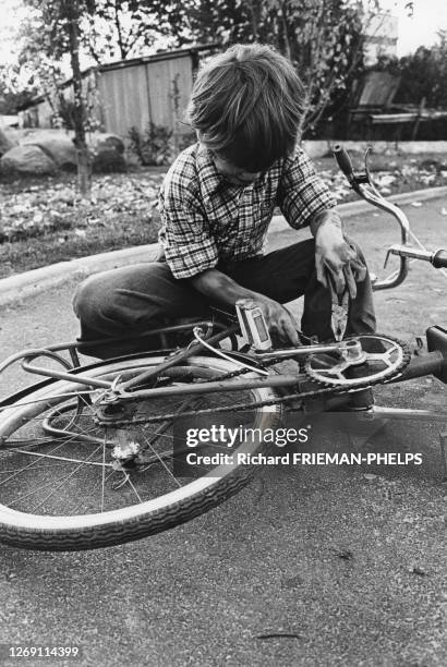 Enfant réparant la chaîne de son vélo, circa 1970, France.