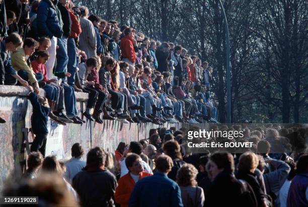 Berlinois assis sur le mur lors de la chute du Mur de Berlin, le 10 novembre 1989, Allemagne.