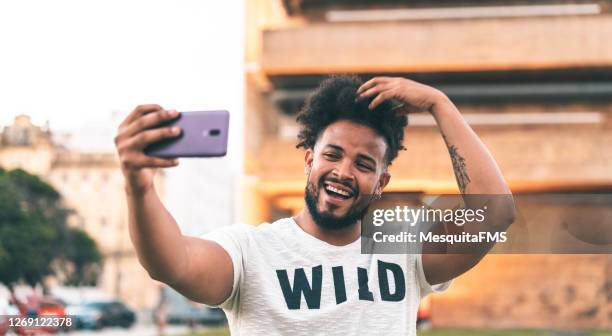 homem vaidoso tirando uma selfie ao ar livre - t shirt com logótipo - fotografias e filmes do acervo
