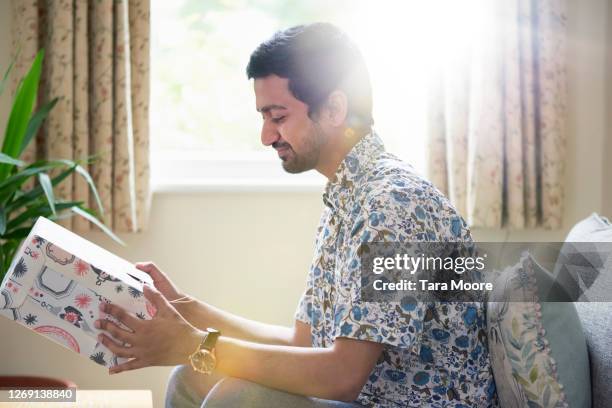 man opening present at home - open gift box stock pictures, royalty-free photos & images