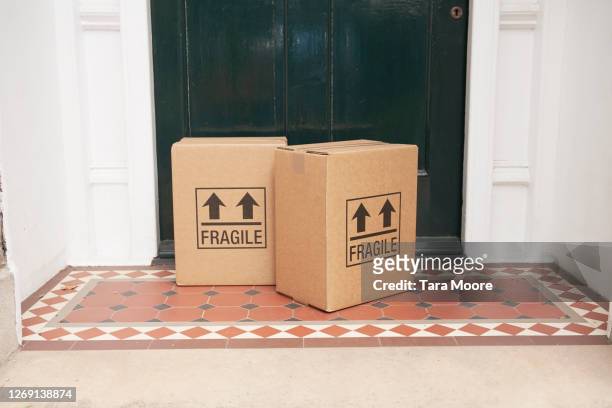 packages left by door at house - brick house door stock pictures, royalty-free photos & images