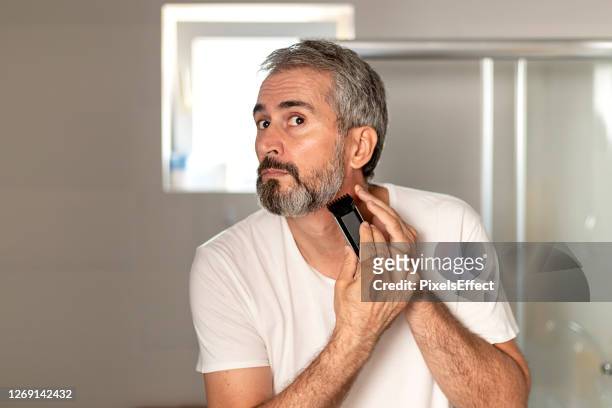 homem barbudo maduro bonito aparando sua barba - clippers - fotografias e filmes do acervo