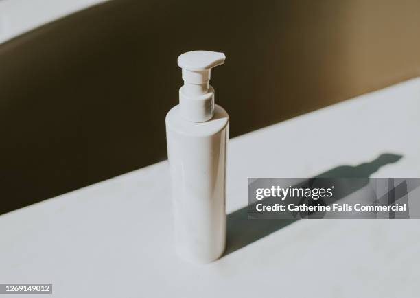 plain white container with pump dispenser sits on a white surface - hair conditioner stock pictures, royalty-free photos & images