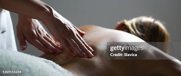 donna che si fa massaggio alla schiena - massaggiare foto e immagini stock