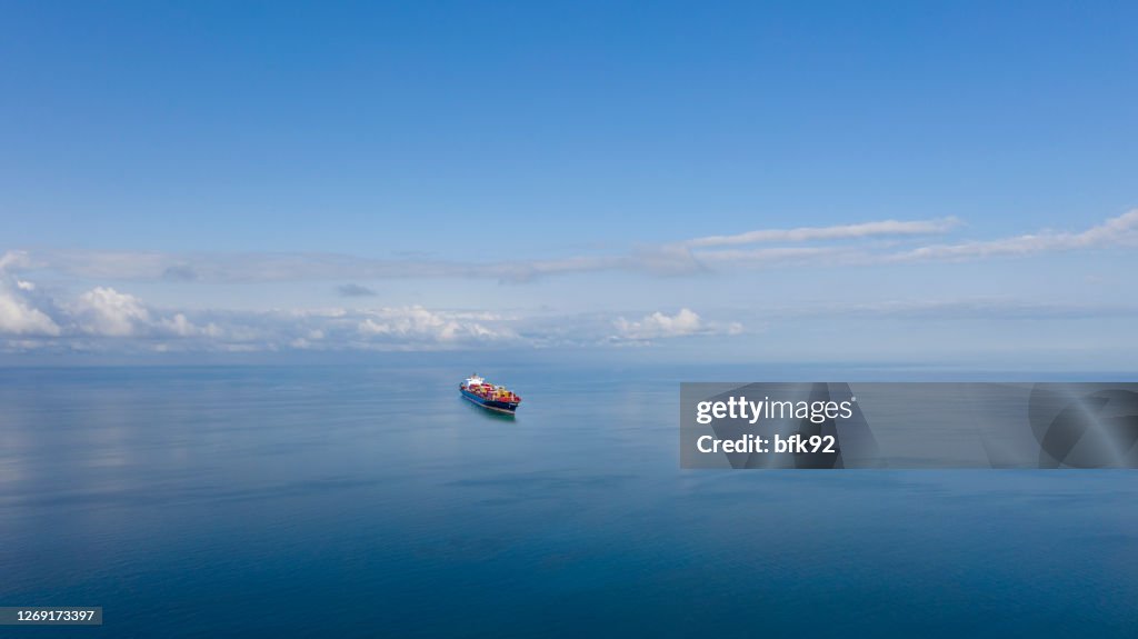 Luftaufnahme eines einzigen großen Frachtschiffs auf See über sonnigem blauen Himmel