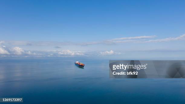 luftaufnahme eines einzigen großen frachtschiffs auf see über sonnigem blauen himmel - containerschiff stock-fotos und bilder