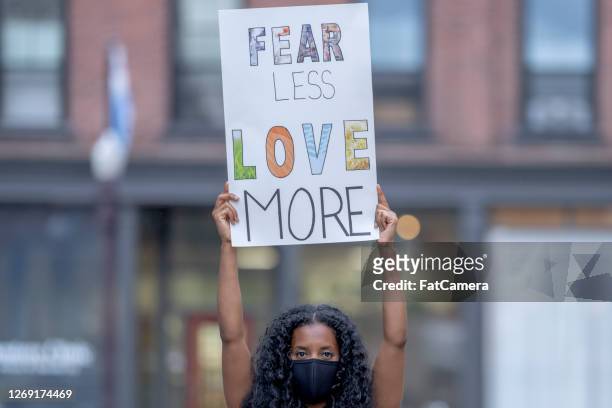 beautiful african american woman holding a protest sign - anti racism stock pictures, royalty-free photos & images