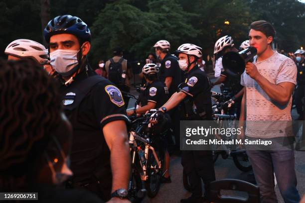 Police officers surround Jacob Wohl as he taunts protesters during a "Trump/Pence Out Now" rally at Black Lives Matter plaza August 27, 2020 in...