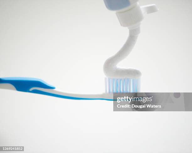 applying toothpaste to blue toothbrush, close up. - toothpaste imagens e fotografias de stock