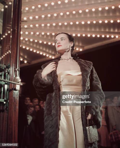 Woman wears a fur coat over an ivory strapless evening dress as she enters a theatre for a special performance in the West End of London in November...