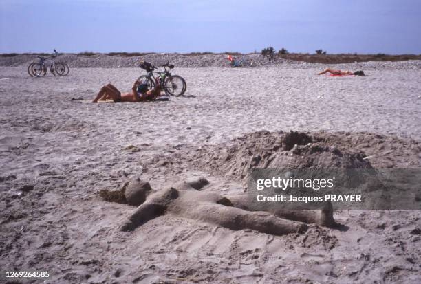 Corps féminin sculpté en sable sur une plage en août 1993 dans l'Hérault, France.