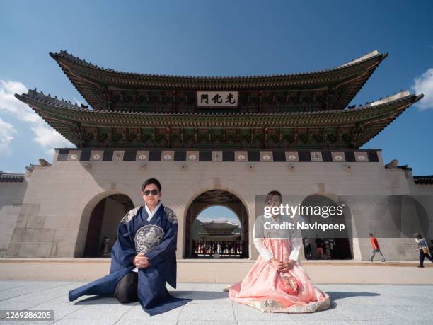 asian tourists in korean traditional costume kneeling in front of gyeongbokgung palace, seoul, korea - korean culture photos et images de collection