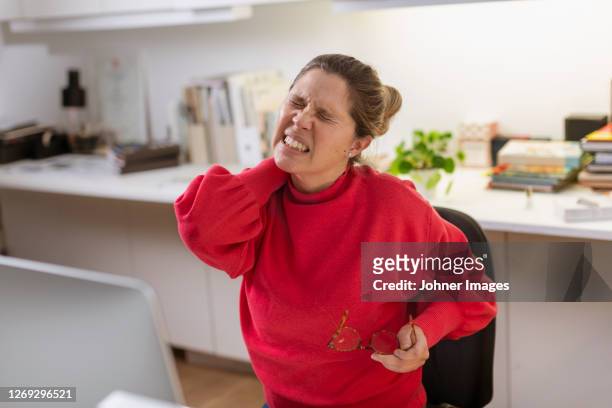 woman massaging her neck at desk - hand back lit stock pictures, royalty-free photos & images