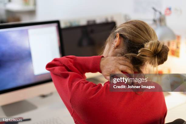 woman massaging her neck at desk - work stress stockfoto's en -beelden