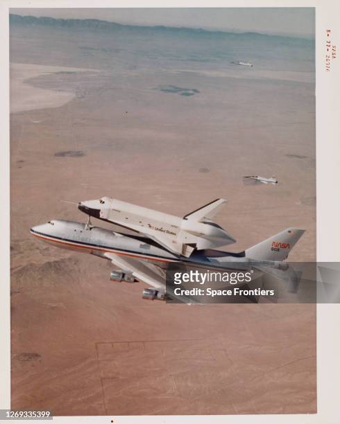 Space Shuttle Enterprise rides piggyback atop NASA 905, a 747 carrier aircraft flies over the desert and mountains of southern California during the...