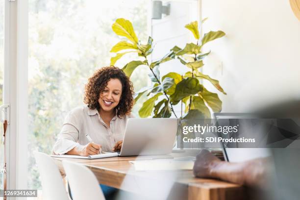 frau lächelt bei der arbeit von zu hause aus mit unkenntlich mann - ehefrau stock-fotos und bilder