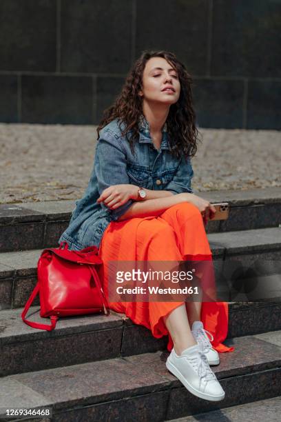 young woman with closed eyes sitting on stairs enjoying the sun - skirt stock pictures, royalty-free photos & images