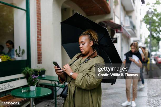 woman waiting in line at restaurant - white and black women and umbrella stockfoto's en -beelden