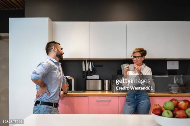 smiling male and female business colleagues talking while enjoying coffee break at cafeteria - cafeteria stock pictures, royalty-free photos & images