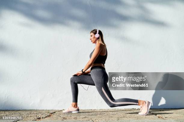 woman listening to music while exercising in city - lunge imagens e fotografias de stock