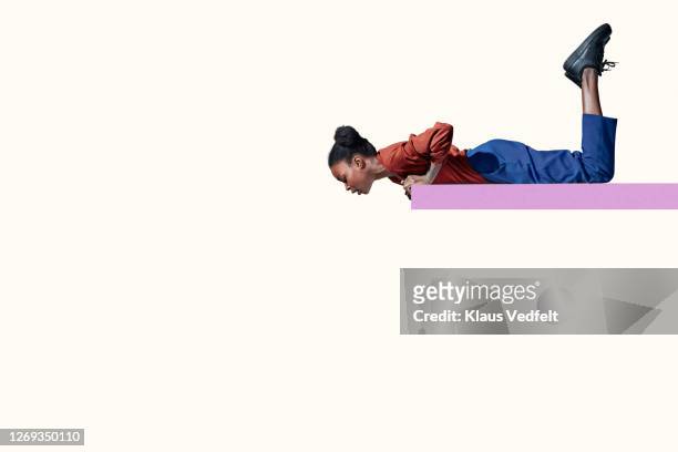 young woman lying on red ramp while looking down - de bruços imagens e fotografias de stock