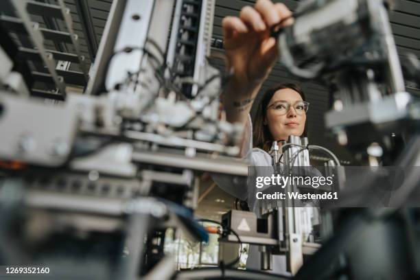 close-up of young woman examining machinery in laboratory - ingenieurwesen stock-fotos und bilder