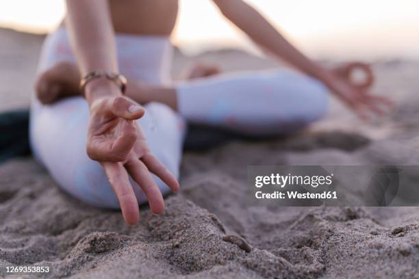 close-up of young woman meditating on sand at beach - mudra stock-fotos und bilder