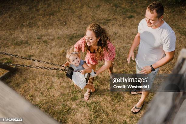 happy girl with parents on a swing - aerial view of childs playground stock pictures, royalty-free photos & images