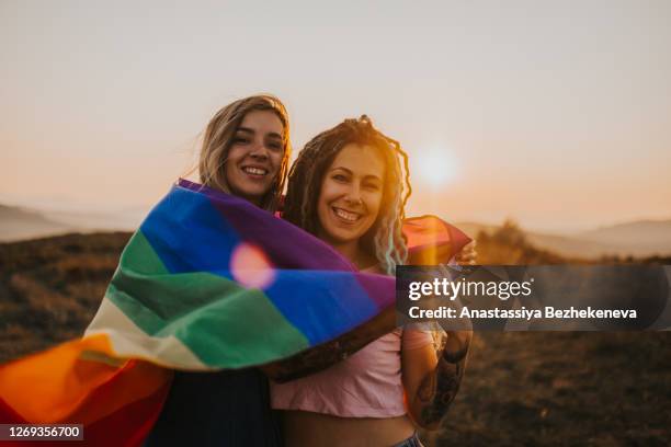 two young laughing happy woman couple hugging - gay flag stockfoto's en -beelden