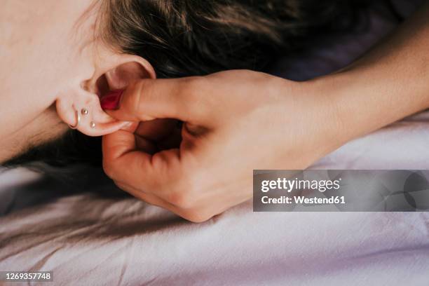 close-up of female therapist giving ear massage to woman in health spa - woman fingers in ears fotografías e imágenes de stock