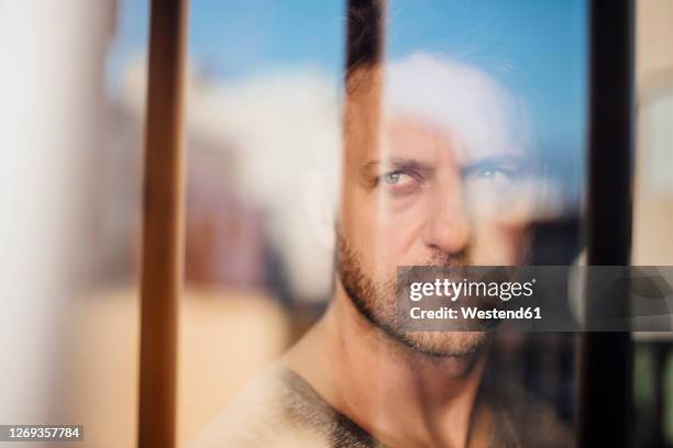 close-up of thoughtful man looking through window seen through glass - photographed through window stockfoto's en -beelden