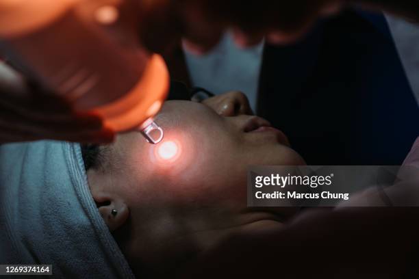 asian chinese female receiving laser facial treatment at facial beauty salon - laser stock pictures, royalty-free photos & images